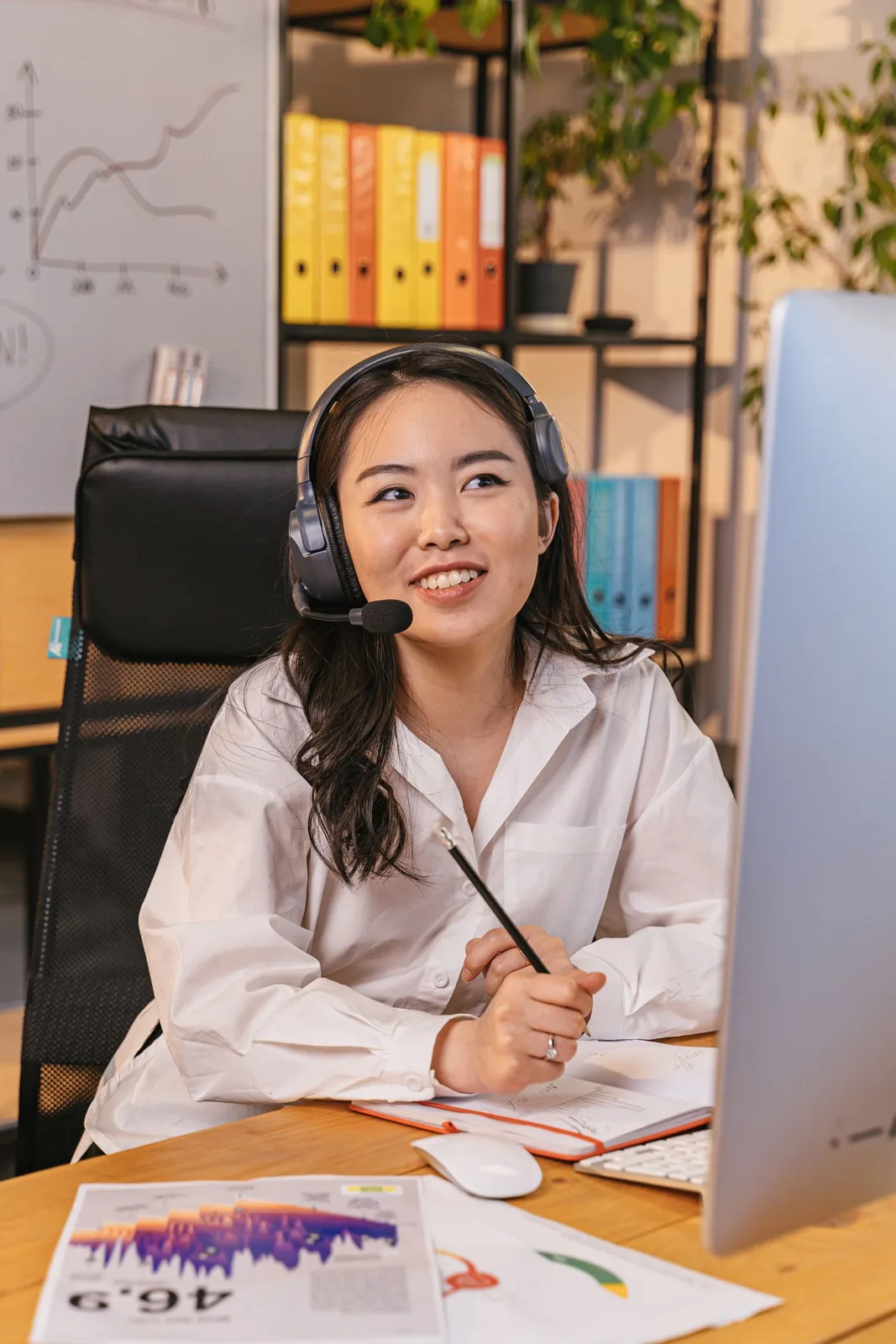 Atendente de headset sorri ao trabalhar numa mesa de escritório