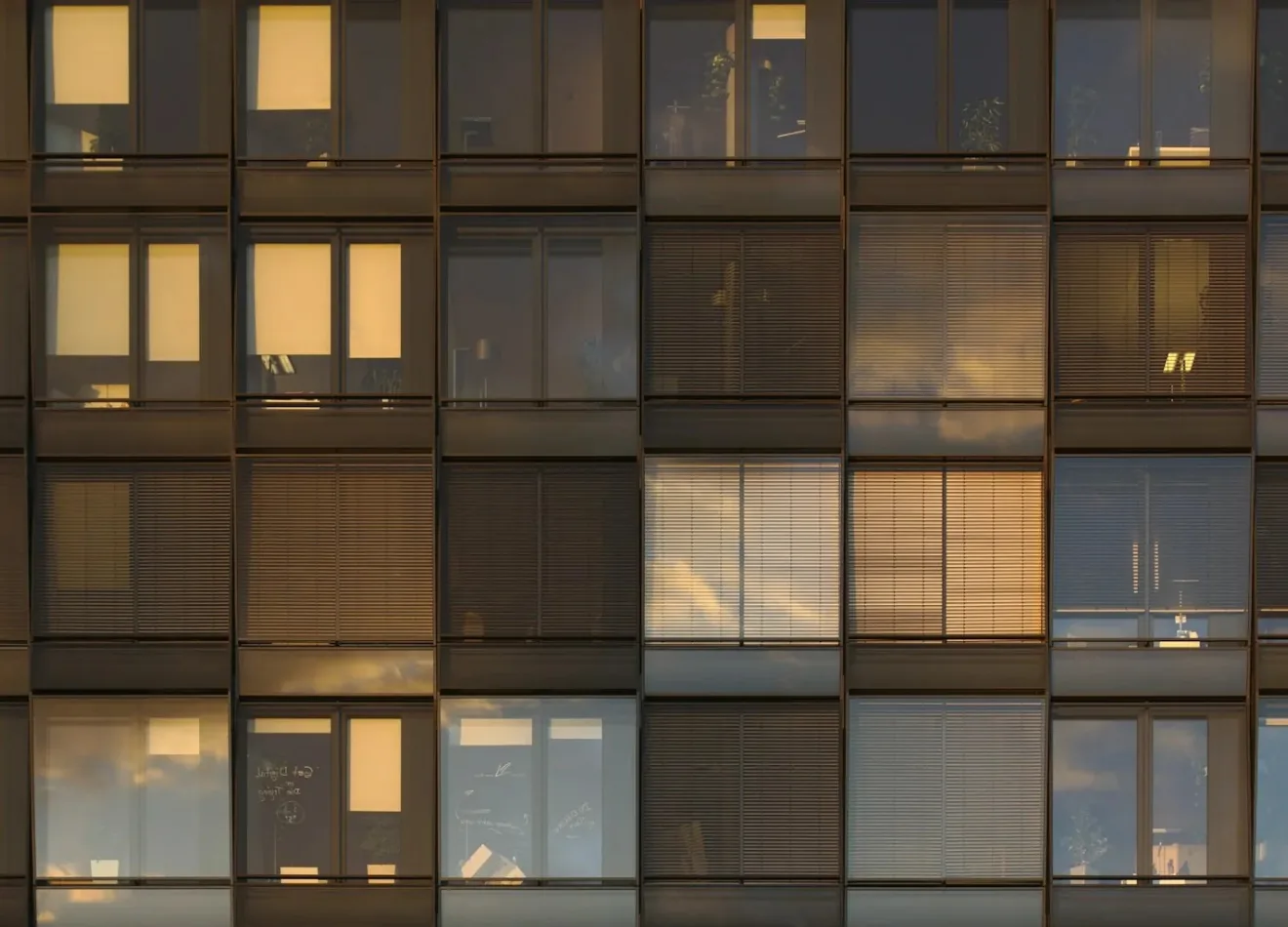 Fachada de prédio residencial ao entardecer, com janelas acesas